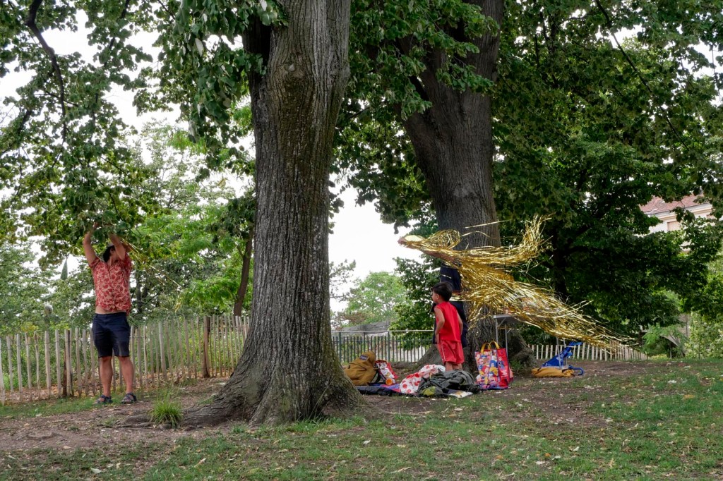 Photo couleur. Marseille, parc Longchamp : un couple installe une guirlande entre deux arbres pour l'anniversaire de leur fils