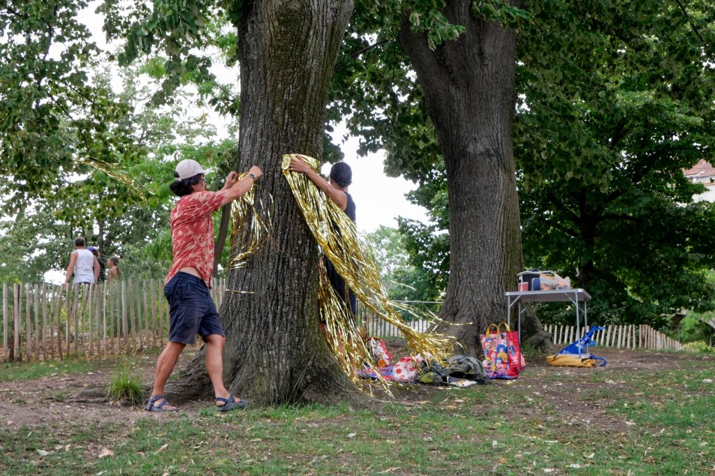 Photo couleur. Marseille, parc Longchamp : un couple installe une guirlande autour d'un arbre pour l'anniversaire de leur fils
