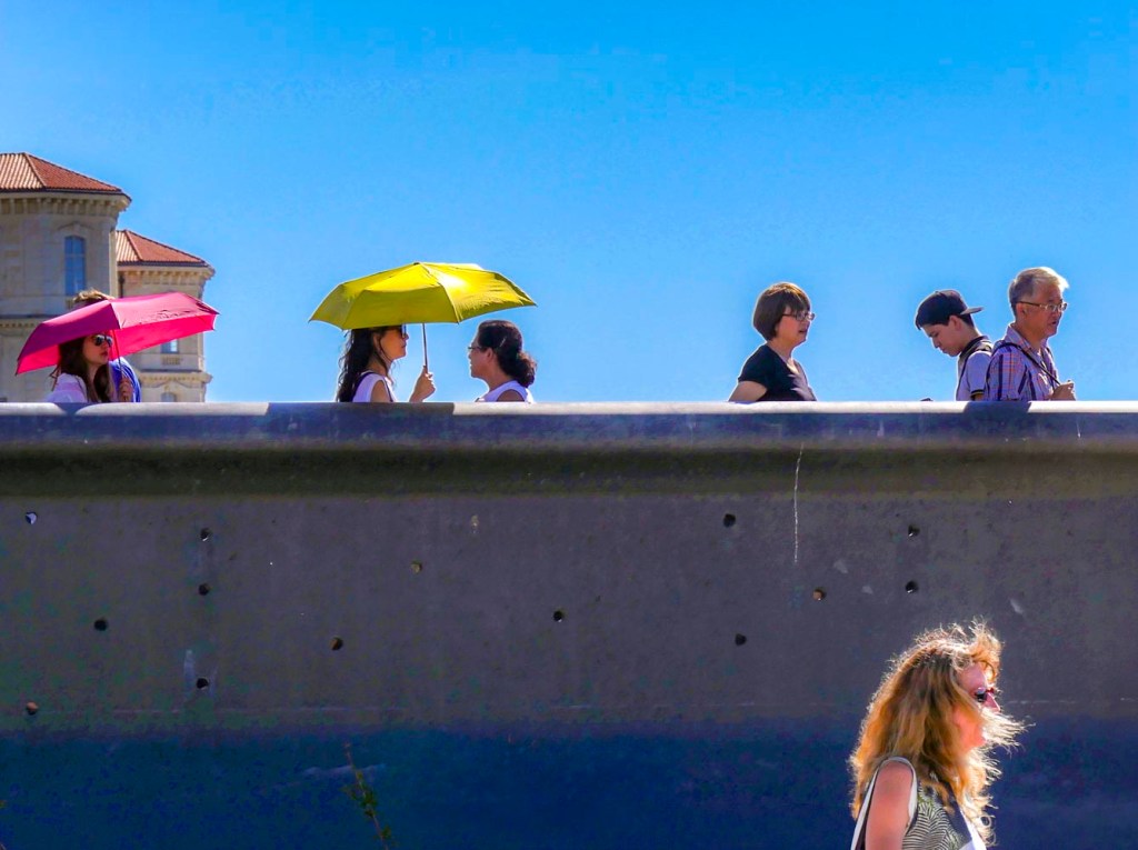 Passerelle du Mucem à Marseille sur fond de ciel bleu ensoleillé. Des personnes marchent sur la passerelle de béton avec des ombrelles pour se protéger du soleil