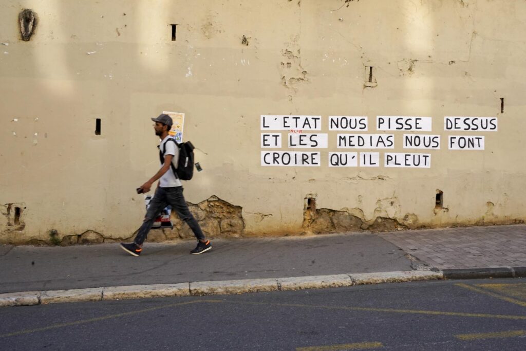 Marseille, mur avec une inscription provocatrice et la silhouette d'un piéton qui vient de passer devant le graffiti